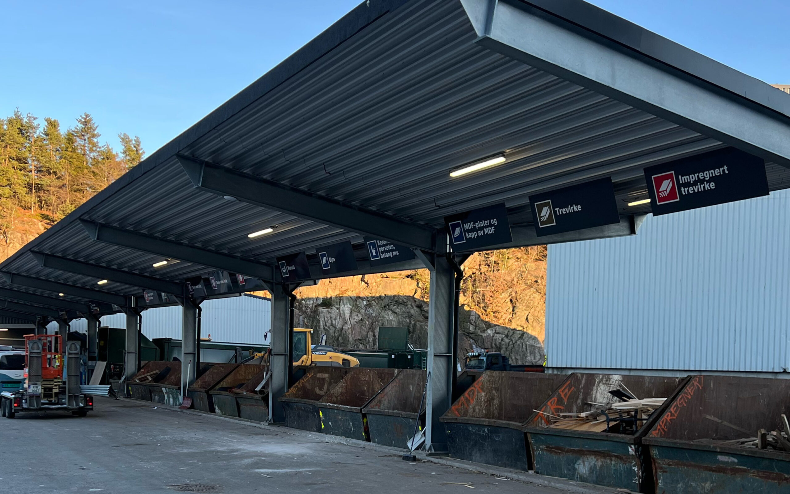 Containere på gjenvinningsstasjon på Støleheia. Sår på rekke og rad, under halvtak.