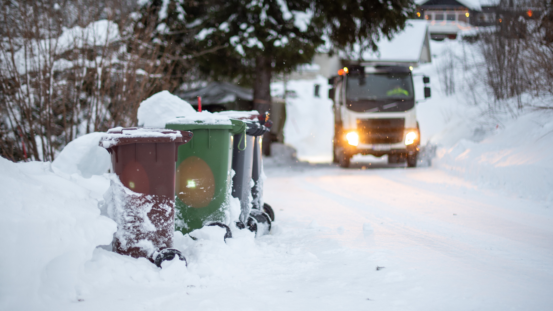 Renovasjonsbil som henter dunker om vinteren etter stort snøfall.