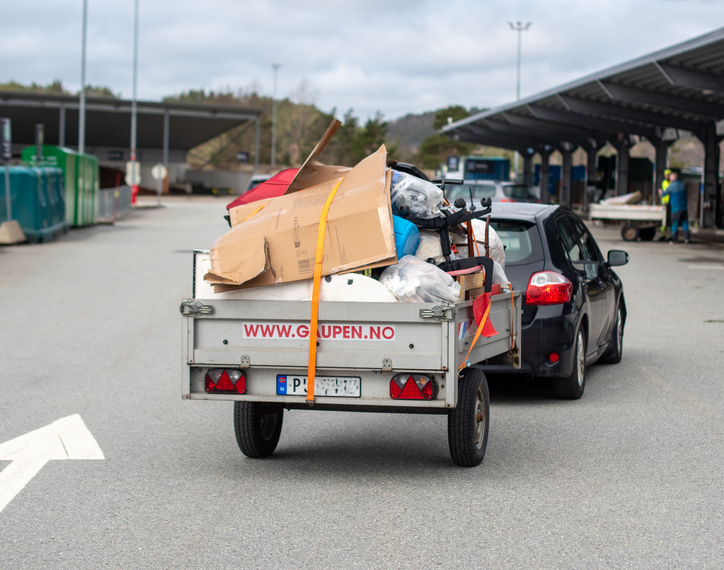 Bil og fullastet tilhenger med avfall på vei inn til en gjenvinningsstasjon.
