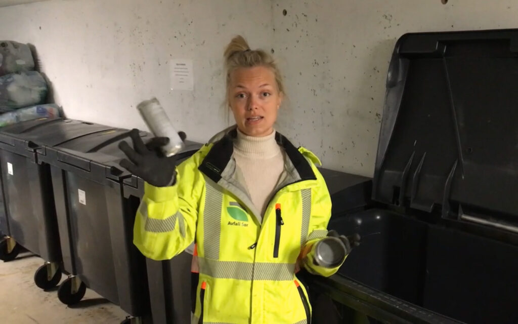 Ansatt som holder opp eksempler på glass- og metallemballasje.