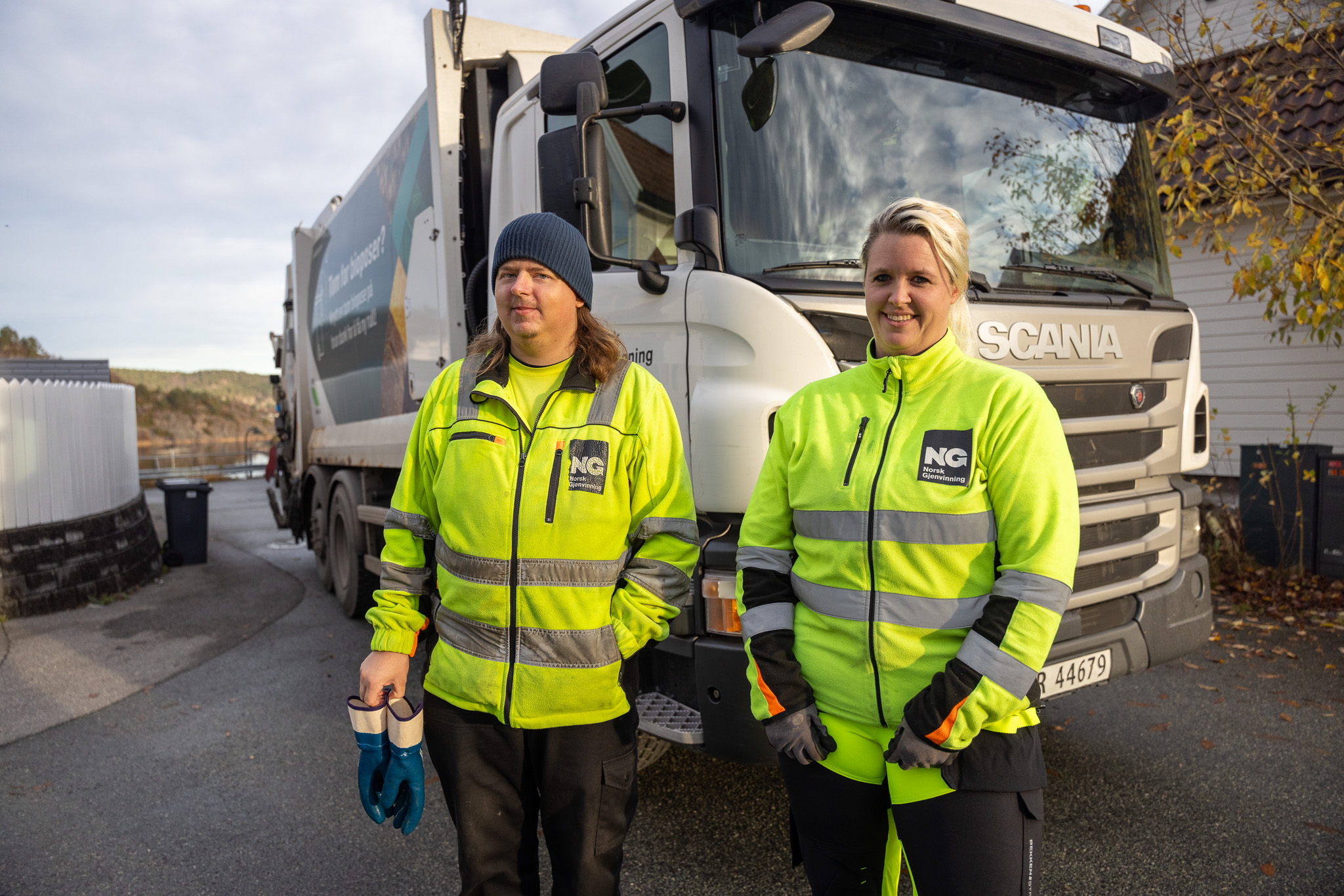 Renovatører foran renovasjonskjøretøy i gate.