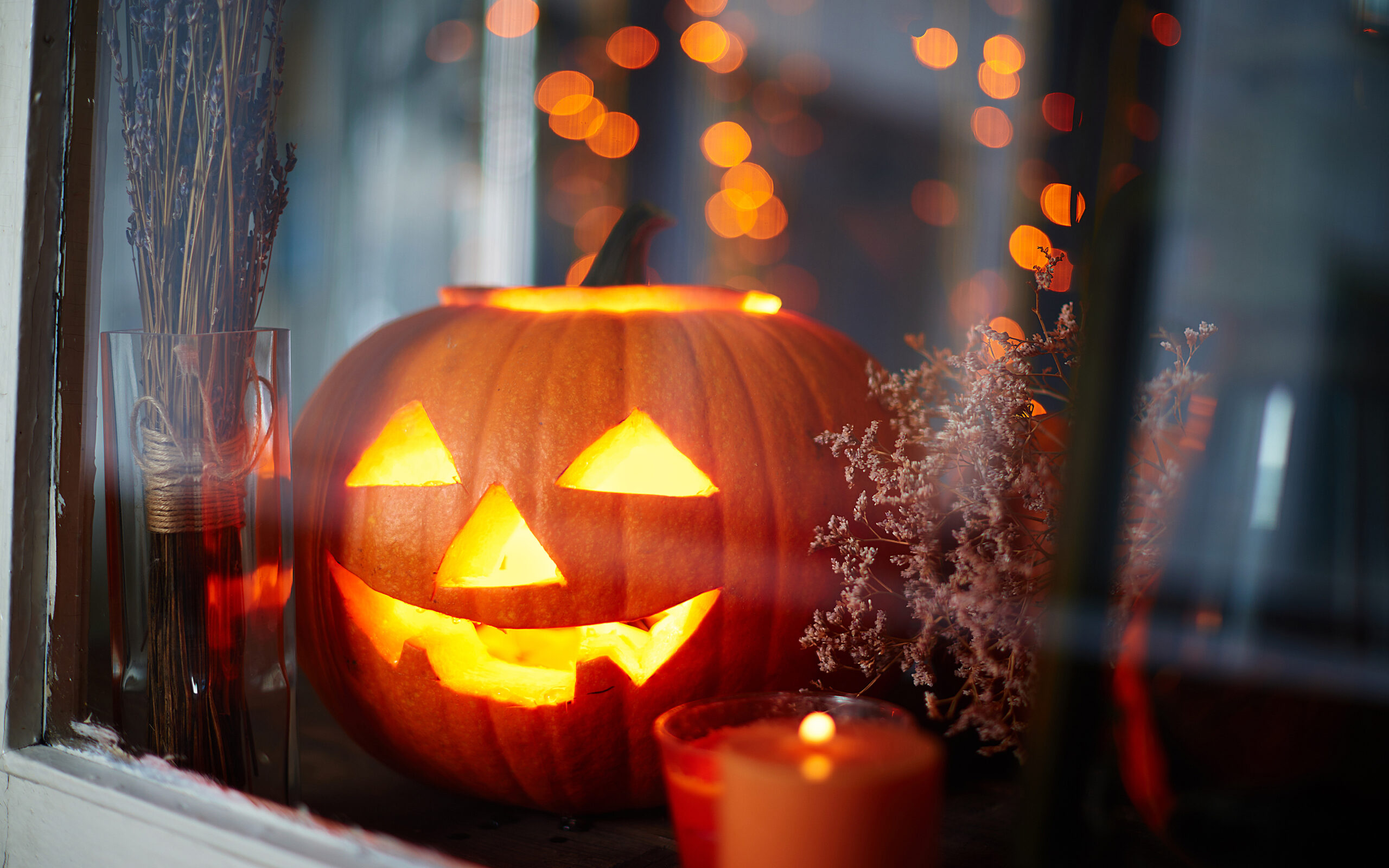 Skummelt utskåren gresskar med teslys inni som står i vinduskarm.