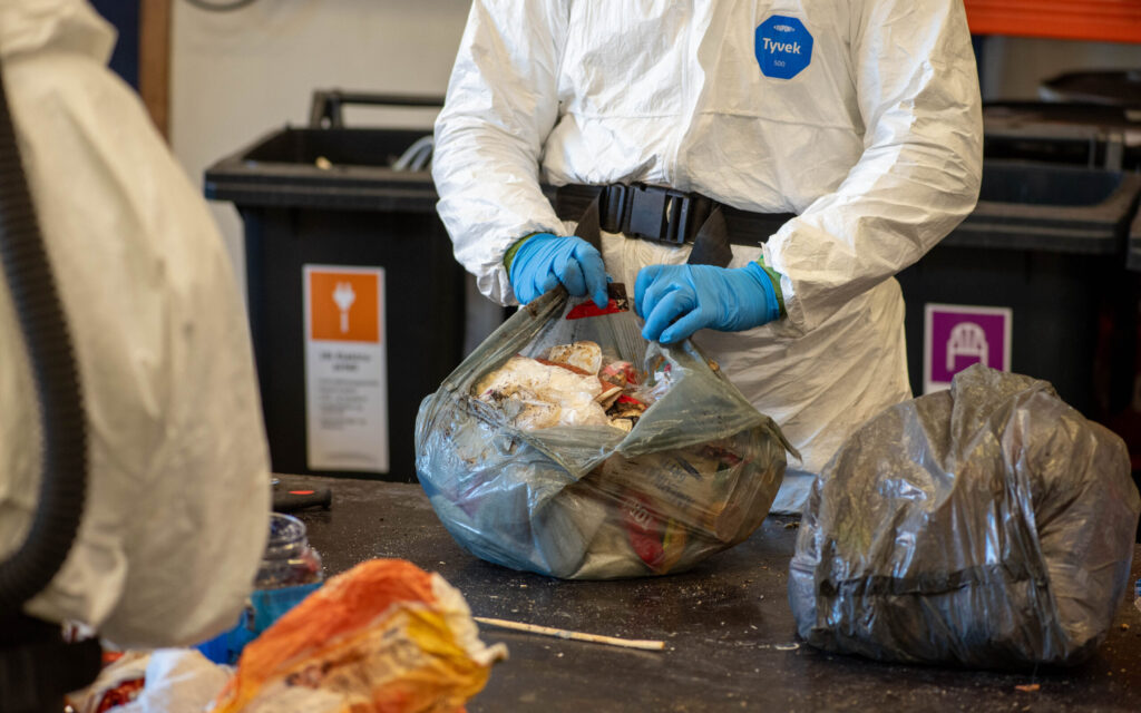 Medarbeider som åpner avfallspose i forbindelse med sorteringsundersøkelse av restavfall.