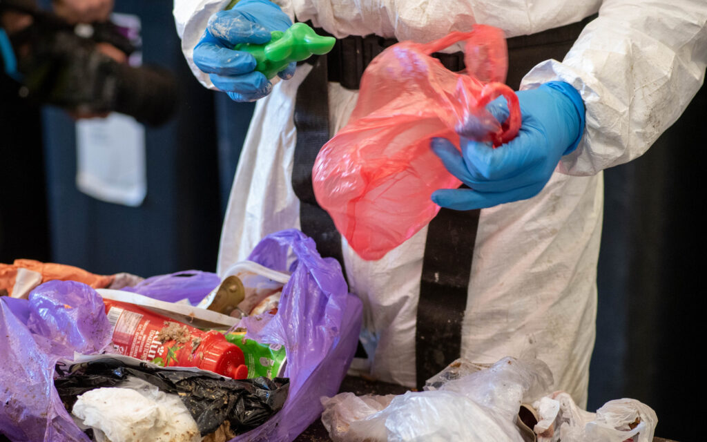 Medarbeider som åpner avfallspose i forbindelse med sorteringsundersøkelse av restavfall.