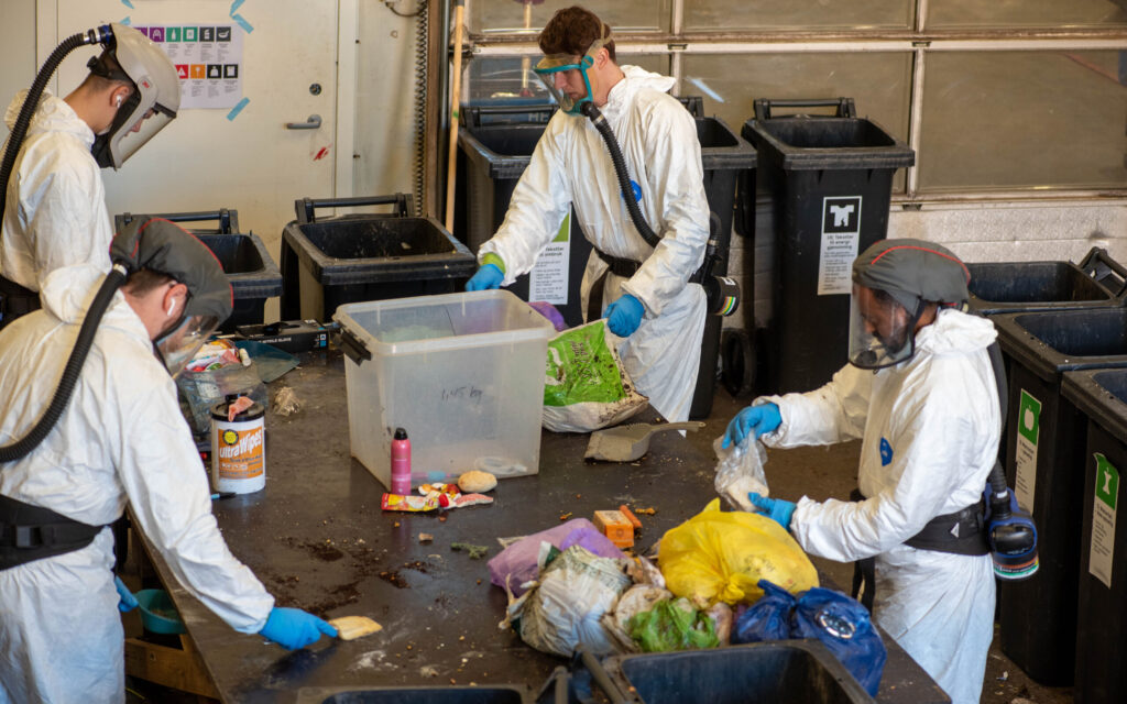 Medarbeidere som åpner avfallsposer i forbindelse med sorteringsundersøkelse av restavfall.