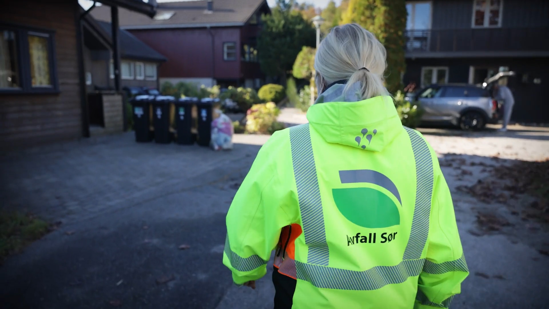 Ansatt i Avfall Sør som går mot avfallsdunker utenfor bolig.