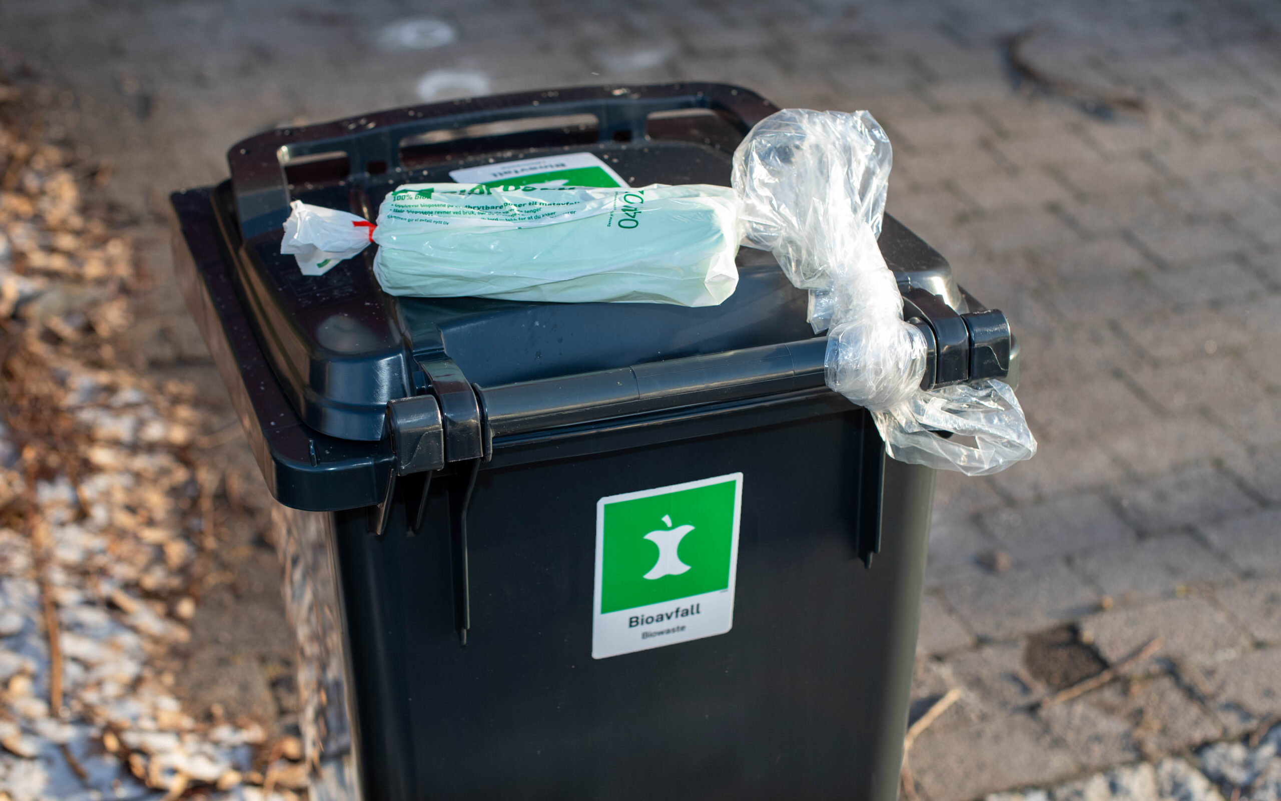 Plastpose knyttet til bioavfallsdunk, og ny rull med bioposer som er lagt oppå dunken av renovatør.