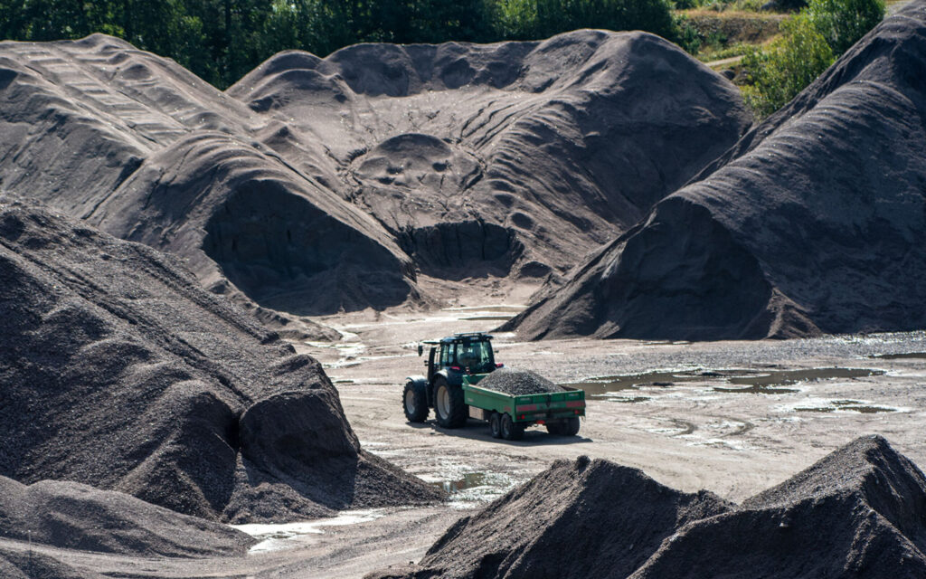 Traktor med vogn som kjører på pukkverk.